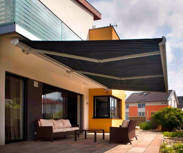 Tenda da sole a bracci in tessuto grigio estesa sopra il patio di un'abitazione
