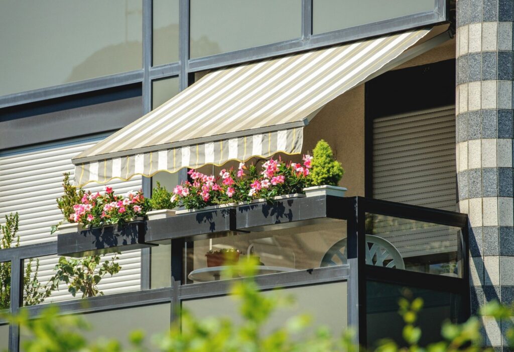 Tenda da sole a righe verdi e bianche sopra un balcone con fioriere